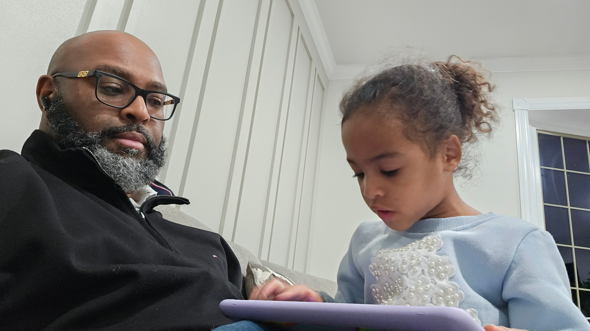 TC Bell spending time with a child while reading from a tablet